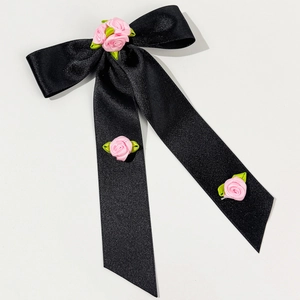 Détail d'un nœud papillon en satin noir avec roses en tissu rose faites à la main et feuilles