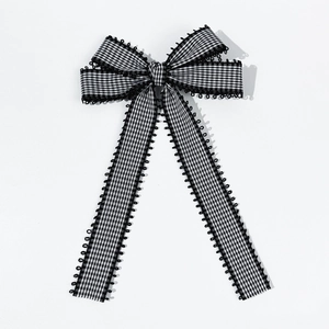 Detail of checkered fabric bow hair clip with black lace trim and long ribbon tails