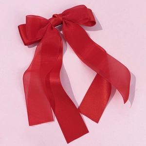 Detail of red double-layer mesh bow hair clip with elegant long ribbons on pink background