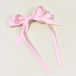 Pink satin ribbon bow hair clip with elegant long streamers and wavy lace edges