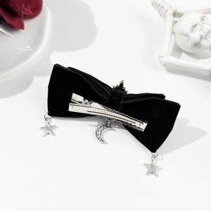Macro shot of gothic black velvet bow hair clip with silver star and moon pendants