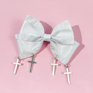 Close-up of white ribbon hair bow with silver gothic cross pendants on pink background