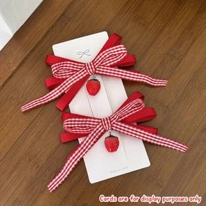 Detailed view of red checkered strawberry bow hair clips on white card display