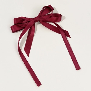 Close-up of wine red satin bow hair clip with layered ribbons and serrated edges