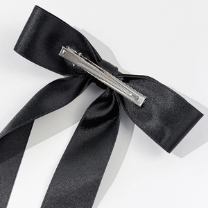 Détail d'un nœud papillon en satin noir avec pince crocodile en métal argenté brillant