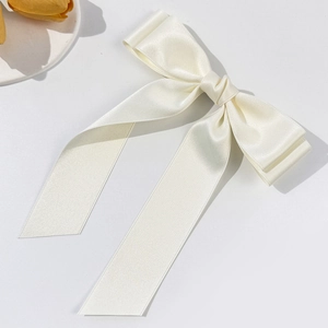 Barrette à cheveux élégante en satin crème avec longs rubans sur fond blanc épuré