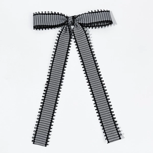 Detail of black and white plaid fabric bow with delicate ring-edge decorative embroidery