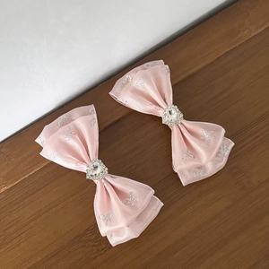 Detail von rosa Satin-Haarschleifen mit Herz-Strasssteinen und Glitzer-Schleifenmuster