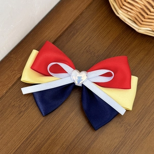 Detail of multi-layer handmade Snow White bow hair clip with a heart shaped gemstone center