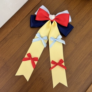 Red navy and yellow layered ribbon bow hair clip with heart center on wood background