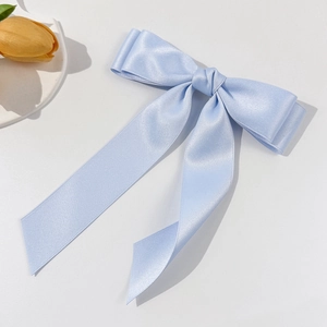 Détail d'une pince à cheveux en satin bleu clair avec texture soyeuse sur fond blanc