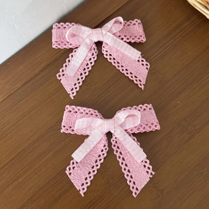 Lot de deux barrettes à nœuds en dentelle rose avec motif ajouré sur fond bois sombre