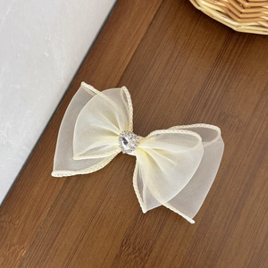Barrette nœud en tulle beige élégante avec cœur en strass sur une surface en bois