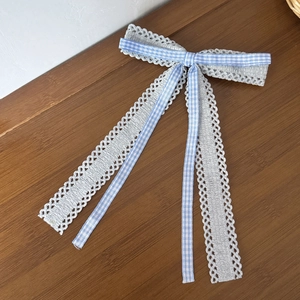 Détail du nœud papillon à carreaux bleus et dentelle grise sur un bureau en bois