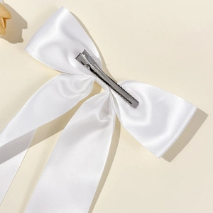 Detail view of the white satin bow hair clip with a silver metal alligator clasp fastener