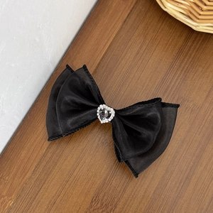 Vue détaillée du nœud en satin noir avec un pendentif en strass en forme de cœur