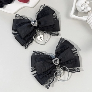 Close-up of black lace bow hair clips with heart charms and cross motifs in gothic style