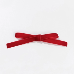 Barrette nœud en velours rouge élégante avec texture fine sur fond blanc épuré