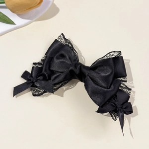 Detail of elegant black lace bow hair clip with layered satin ribbons and delicate lace trim
