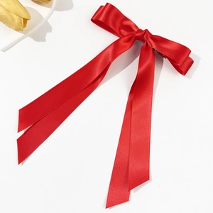 Detail einer roten Satin-Haarklammer mit doppelter Schleife und eleganten langen Bändern