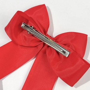 Dettaglio della clip a coccodrillo in metallo su un fiocco in nastro grosgrain rosso