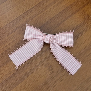 Nahaufnahme der rosa karierten Schleifen-Haarspange mit Spitze und silbernem Metallclip