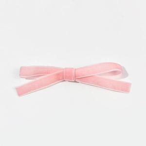 Gros plan détaillé d'une barrette nœud en velours rose avec une texture douce et élégante