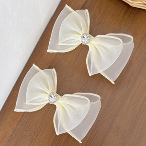 Détail de barrettes nœud en maille avec strass en cœur sur un fond de bois sombre