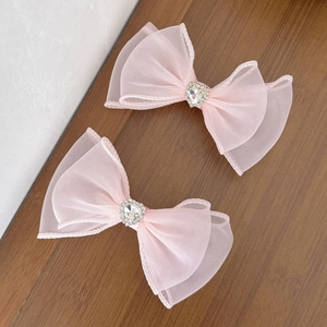 Détail de pinces à cheveux nœuds en maille rose avec cœurs en strass sur bois