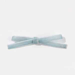 Détail de la pince nœud en velours bleu clair montrant la texture douce du tissu