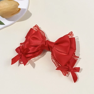 Detailed view of red satin bow hair clip with delicate lace trim and ribbon layers