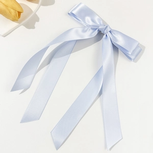 Detail einer eleganten hellblauen Satin-Haarspange mit langen Seidenbändern auf weißem Grund