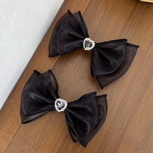 Détail de pinces à cheveux noeud en tulle noir avec cœur en strass sur bois