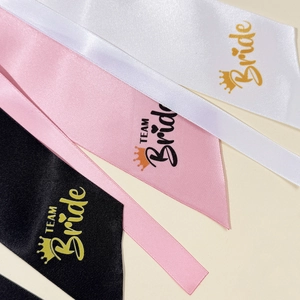 Macro detail of satin ribbons in white pink and black with gold TEAM Bride text