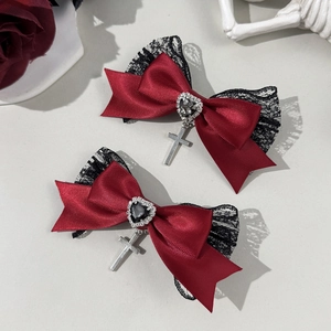 Detalle de pinza gótica de raso rojo con cristal de corazón y colgante de cruz de plata