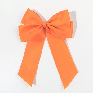 Dettaglio di un fermaglio per capelli con fiocco in nastro grosgrain arancione brillante