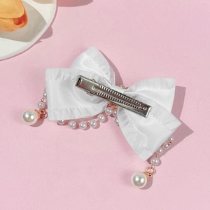 Detail of white satin bow hair clip with pearl tassels and rose gold metal alligator clip