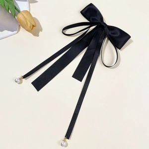 Détail du nœud en satin noir avec de longs rubans et d'élégants pendentifs en perles blanches