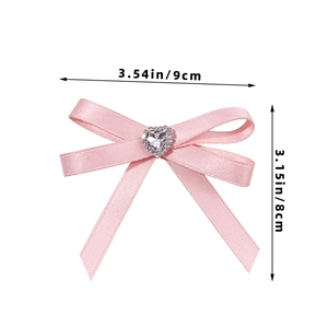 Pink ribbon bow hair clip with heart rhinestone detail showing dimensions 9cm by 8cm