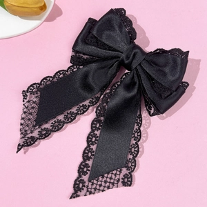 Close-up of black satin hair bow with delicate lace edges and elegant vintage texture