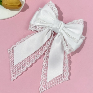 Detailed close-up of a white satin bow hair clip with intricate lace edges and ribbons