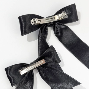 Detail of black satin bow hair clips showing back view and silver metal spring barrette