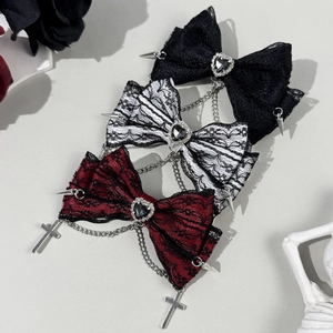 Macro detail of gothic lace bows with heart gems, metal chains, and cross pendants