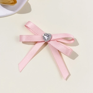 Close-up of pink satin bow hair clip with a sparkling heart-shaped rhinestone center
