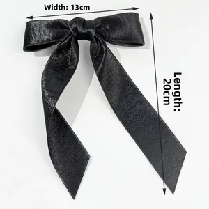 Detail view of large black satin bow hair clip with 13cm width and 20cm length ribbons