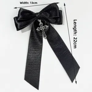 Detail of black satin bow hair clip with silver cross pendant, 13cm wide and 22cm long