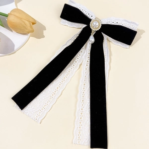 Detailed macro of vintage black velvet bow with white lace and dangling pearl charms