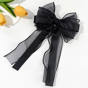 Detail of black layered organza and satin bow hair clip with elegant long ribbons