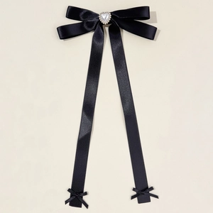 Details einer schwarzen Satin-Haarklammer mit Herzperle und langen Schleifenbändern