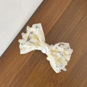 Gros plan sur une pince à cheveux en dentelle florale avec une perle centrale délicate
